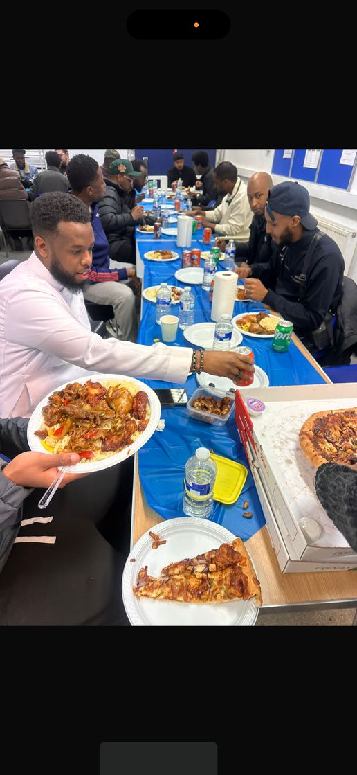 Men sharing food along a long table at the men's Iftar