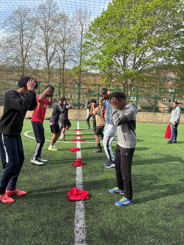 Boys doing a football drill between cones on an outdoor pitch