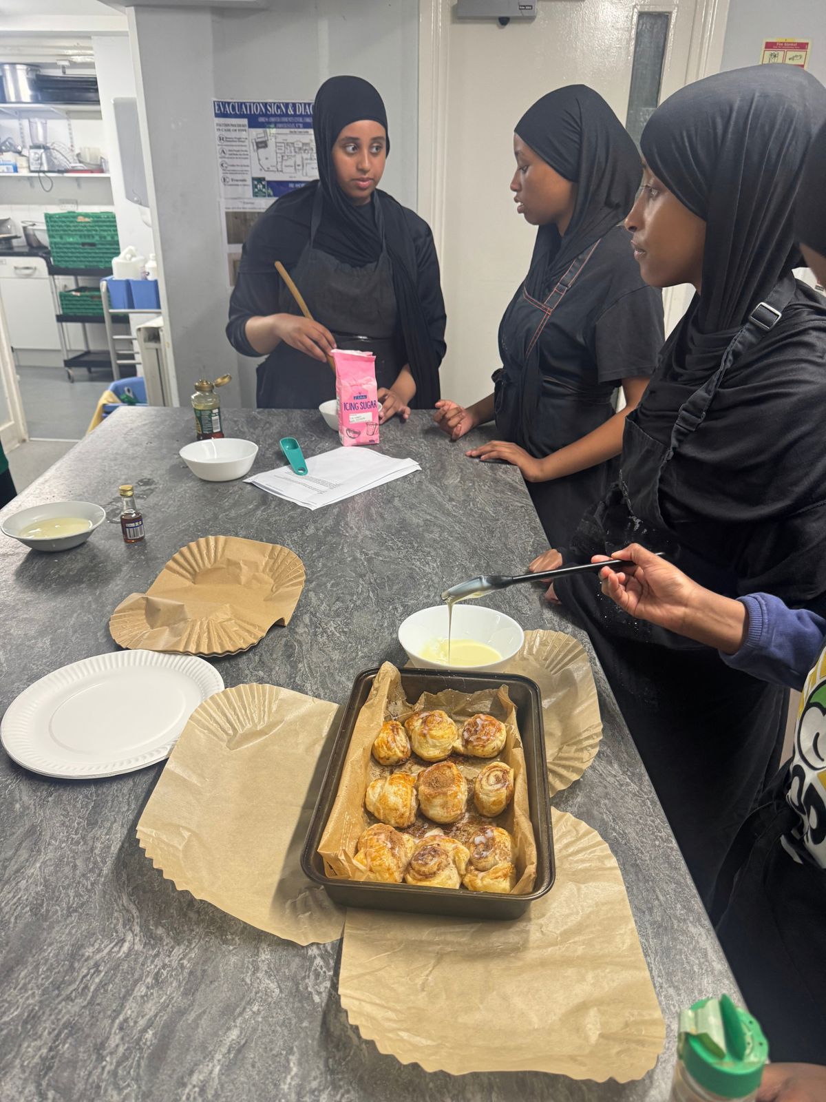 Girls taking part in a baking session, with a tray of freshly baked buns
