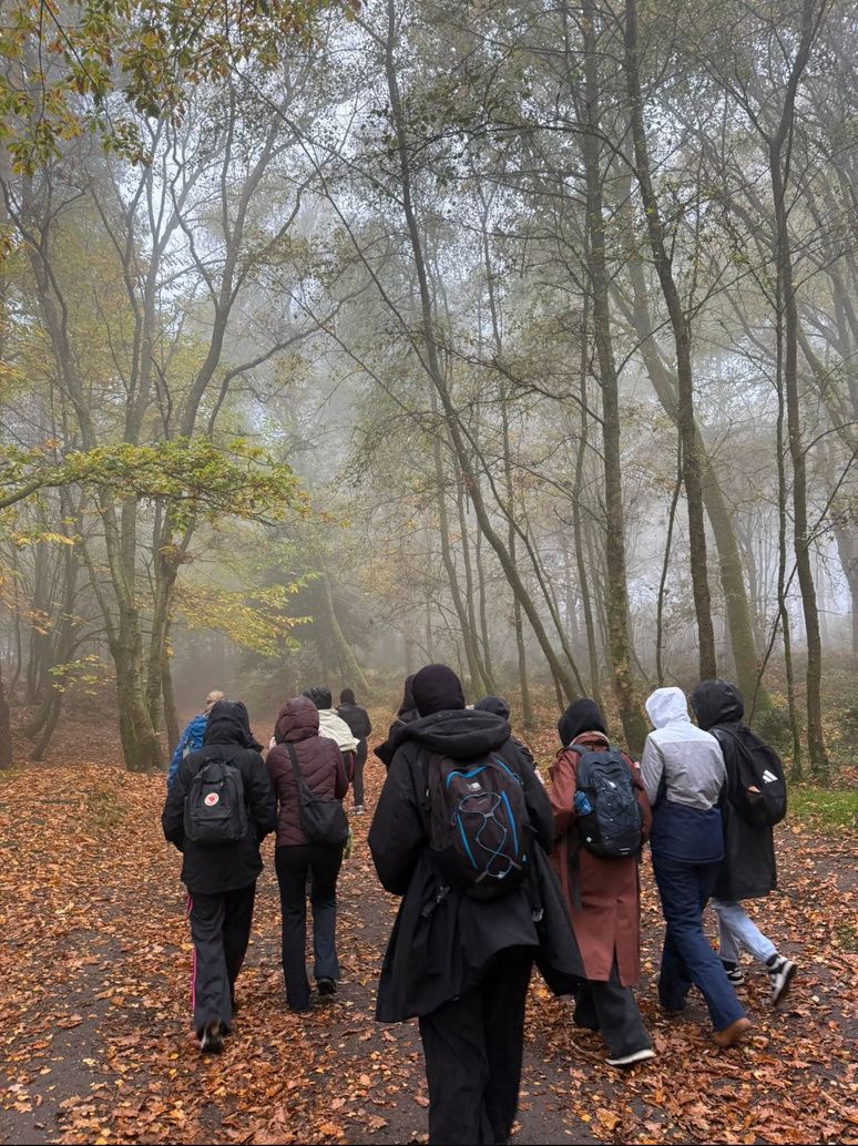 Young women walking along a leafy woodland path on a misty autumn day