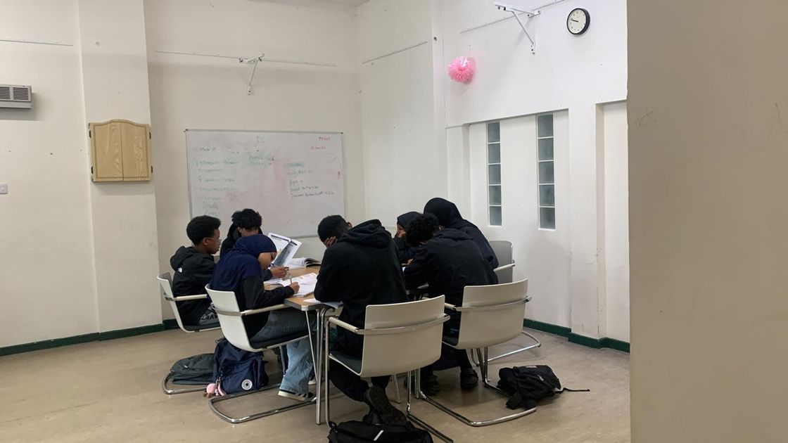 Young people studying together around tables in a classroom during a revision session